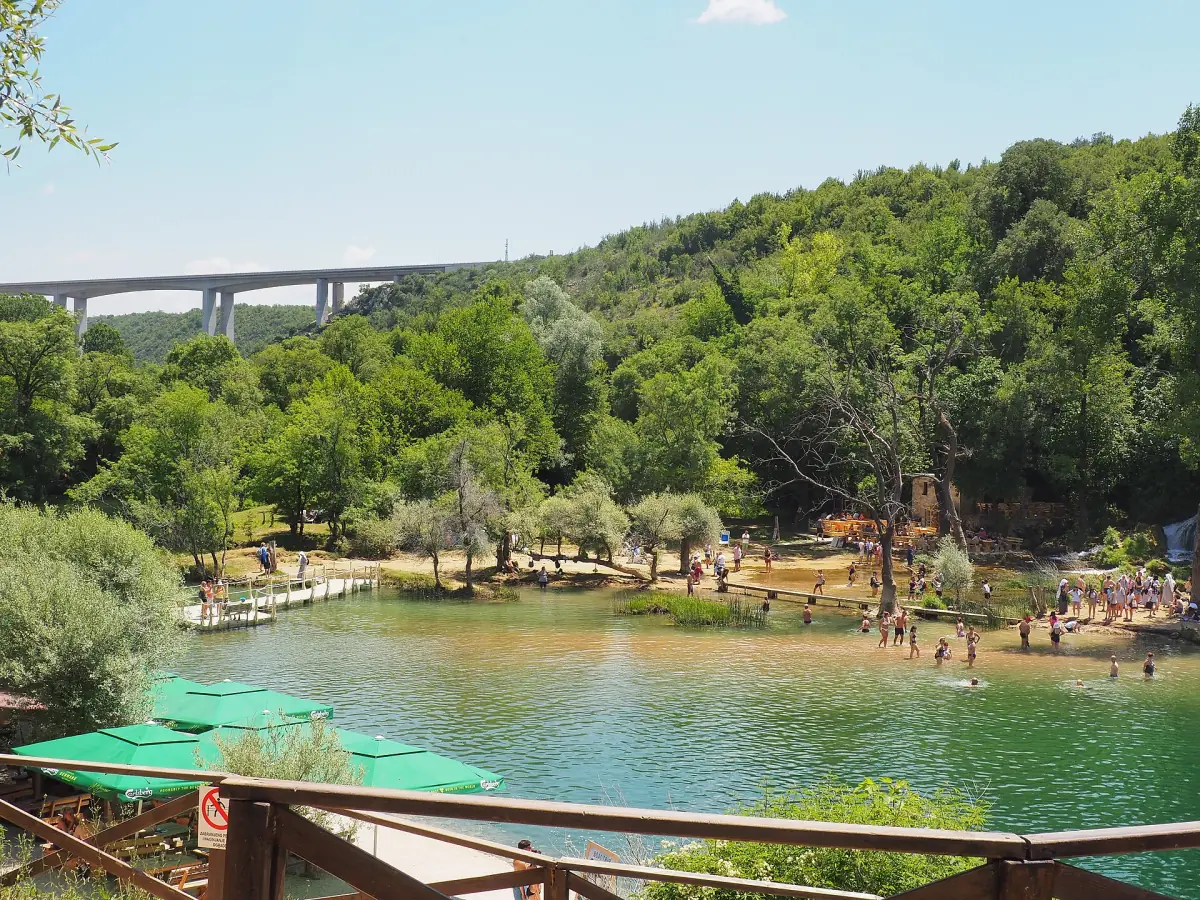 The Kravica pool with its meadow and a viaduct behind